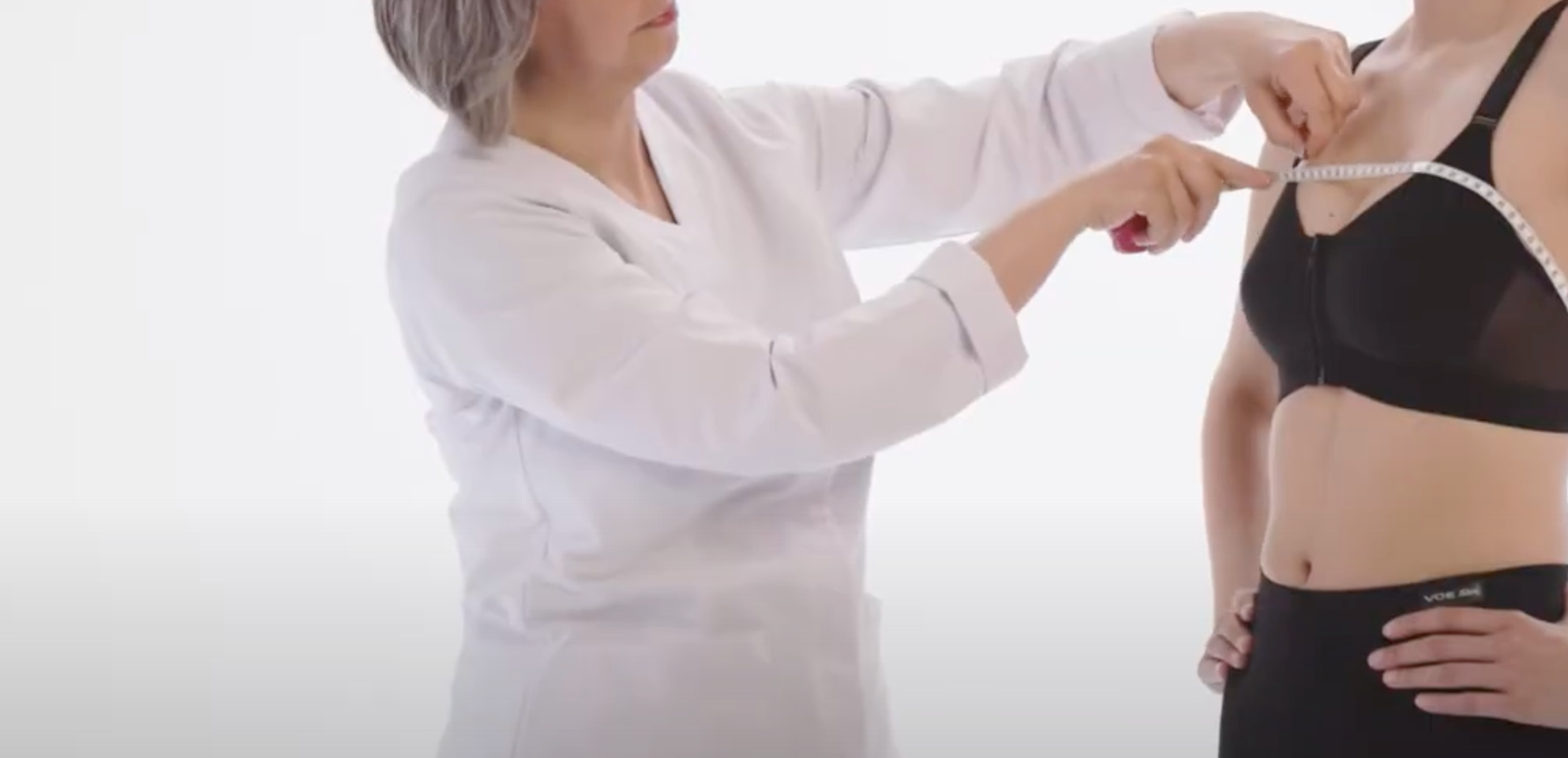 Profesional midiendo con cinta métrica a paciente con prenda de compresión médica postquirúrgica
